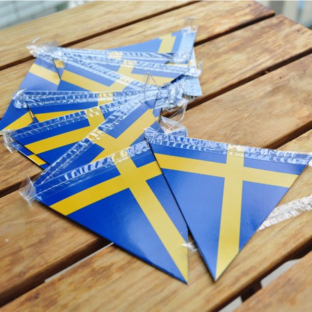 Girlang med sverigeflaggor som ligger mot ett bord.